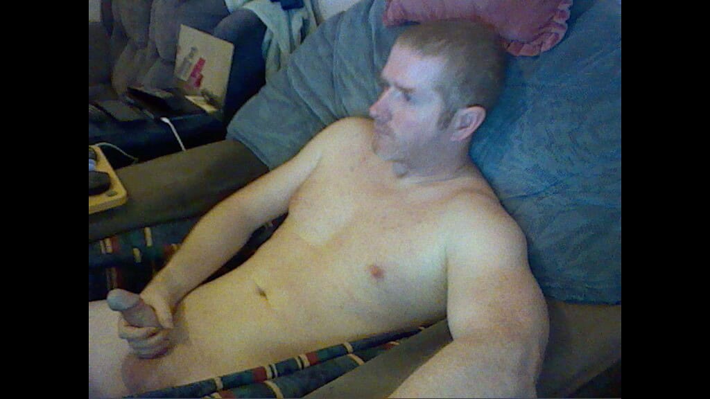 Naturist nudist nude naked penis man relaxing on sofa.