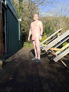 Naturist nudist nude naked penis man standing outdoors in sunlight.