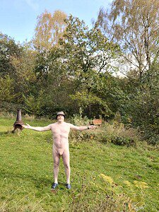 Naturist nudist nude naked penis man standing outdoors with arms wide open.