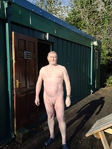 Naturist nudist nude naked penis man standing outside green building.