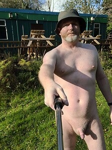 Naturist nudist nude naked penis man taking selfie outdoors in natural environment.