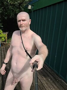 Naturist nudist nude naked penis, man taking selfie outdoors, natural skin tone, bald, serious face.