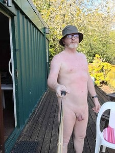 Naturist nudist nude naked penis man taking selfie outdoors in sunlight.