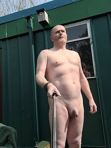 Naturist nudist nude naked penis of a man standing outdoors with a selfie stick.