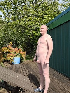 Naturist nudist nude naked penis in outdoor environment with greenery.