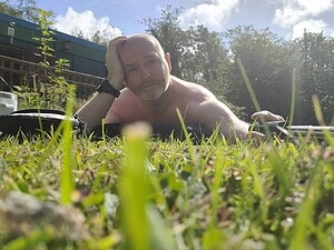 Naturist nudist nude naked penis man lying on grass in outdoor setting.