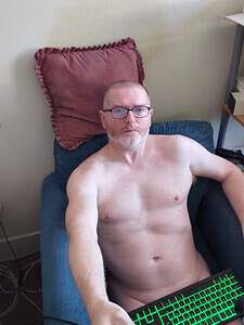 Naturist nudist nude naked penis man relaxing on sofa with pillow.