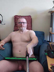 Naturist nudist nude naked penis, man sitting topless on sofa with selfie stick.