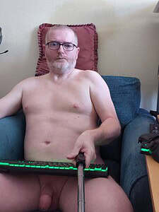Naturist nudist nude naked penis man relaxing on sofa with selfie stick.